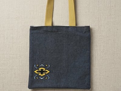 The Onyx Cipher Trace Tote - Black denim bag with mustard yellow straps and geometric embroidery