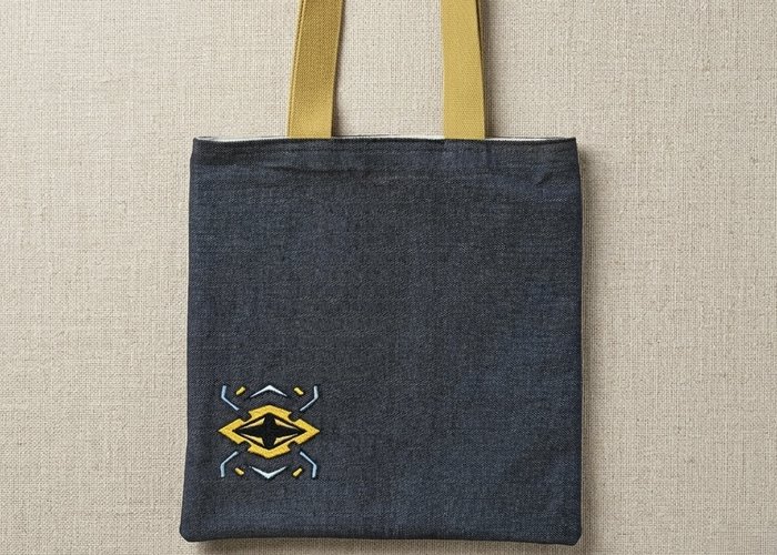 The Onyx Cipher Trace Tote - Black denim bag with mustard yellow straps and geometric embroidery
